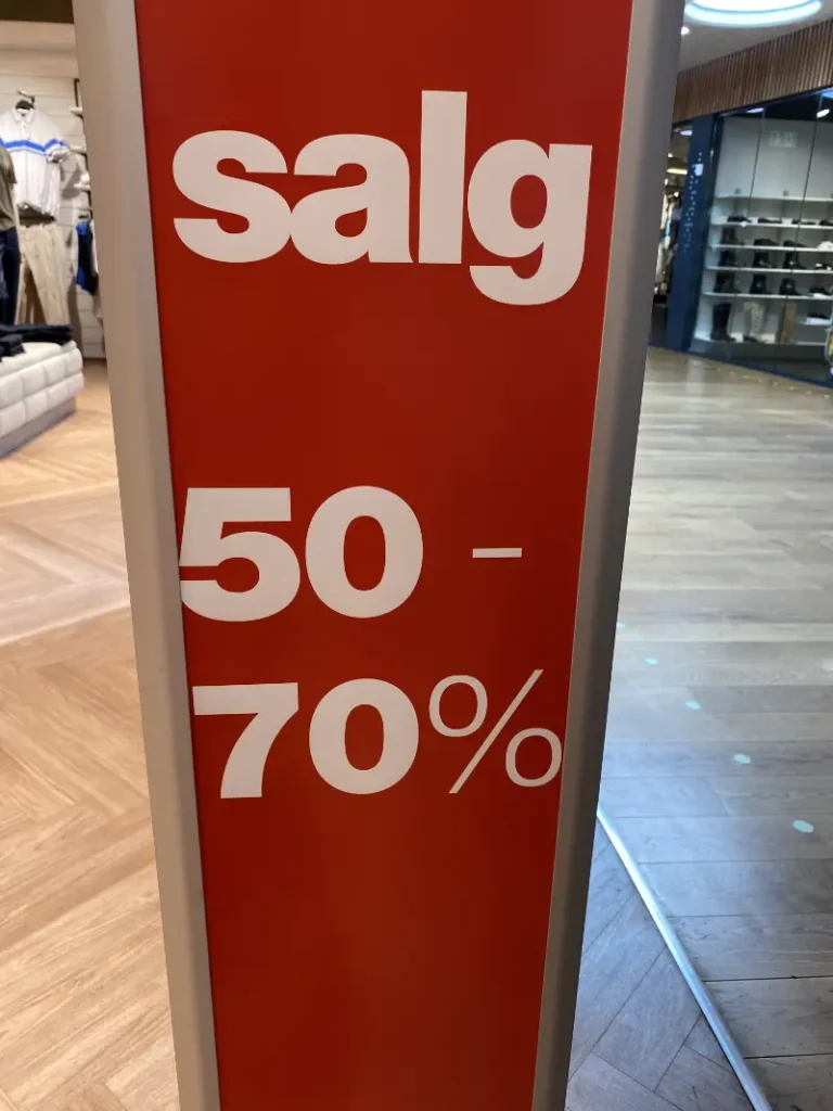 Rødt skilt med teksten "salg 50-70%" i en butik.