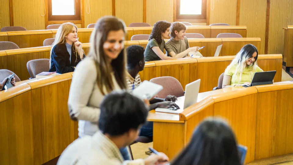 Gruppe studenter i et auditorium som studerer og diskuterer sammen.