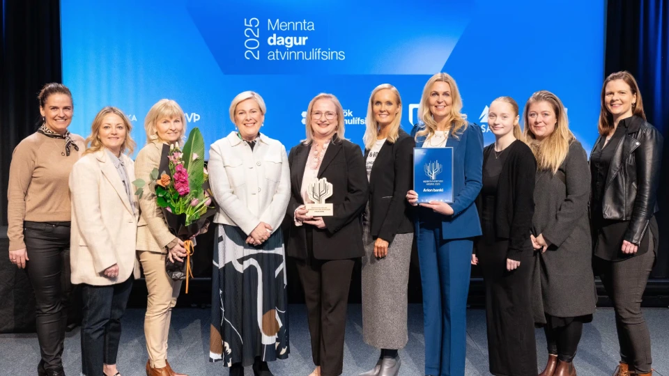 En gruppe kvinner poserer på en scene under "Mennta dagur atvinnulífsins 2025", med en pris og et diplom. En kvinne holder en blomsterbukett. Bakgrunnen er en blå skjerm med arrangementets logo.