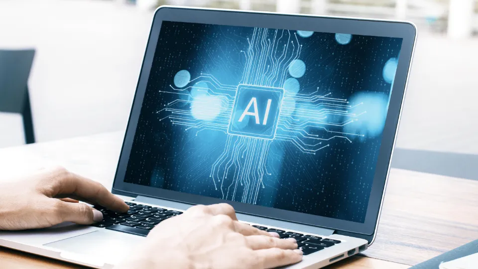 Person som bruker en bærbar datamaskin med et digitalt AI-symbol på skjermen.