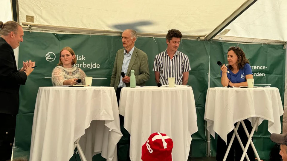 NLL sætter digital inklusion på dagsordenen til Folkemøde 2025 Panel discussion with five people under a tent, featuring microphones and drinks on standing tables, with a green backdrop labeled "Nordisk samarbejde."