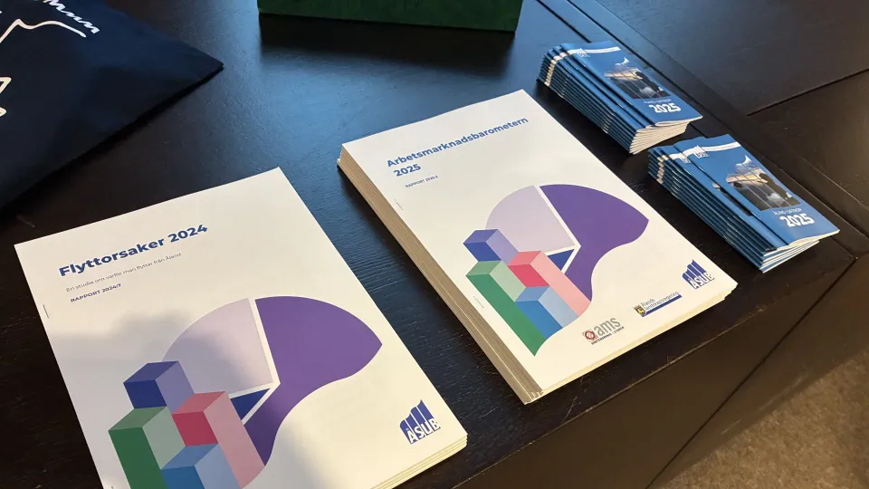 Informationsbroschyrer och rapporter för 2024 och 2025 från ÅSUB och AMS ligger upplagda på ett bord.