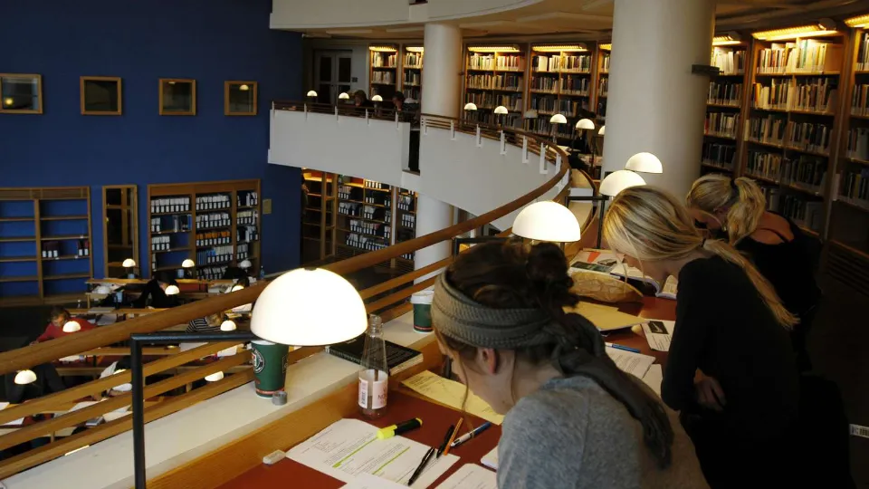 Folkbildningen – En plats för personlig och demokratisk utveckling i en föränderlig värld Studenter studerar vid skrivbord i ett bibliotek med böcker och läslampor.