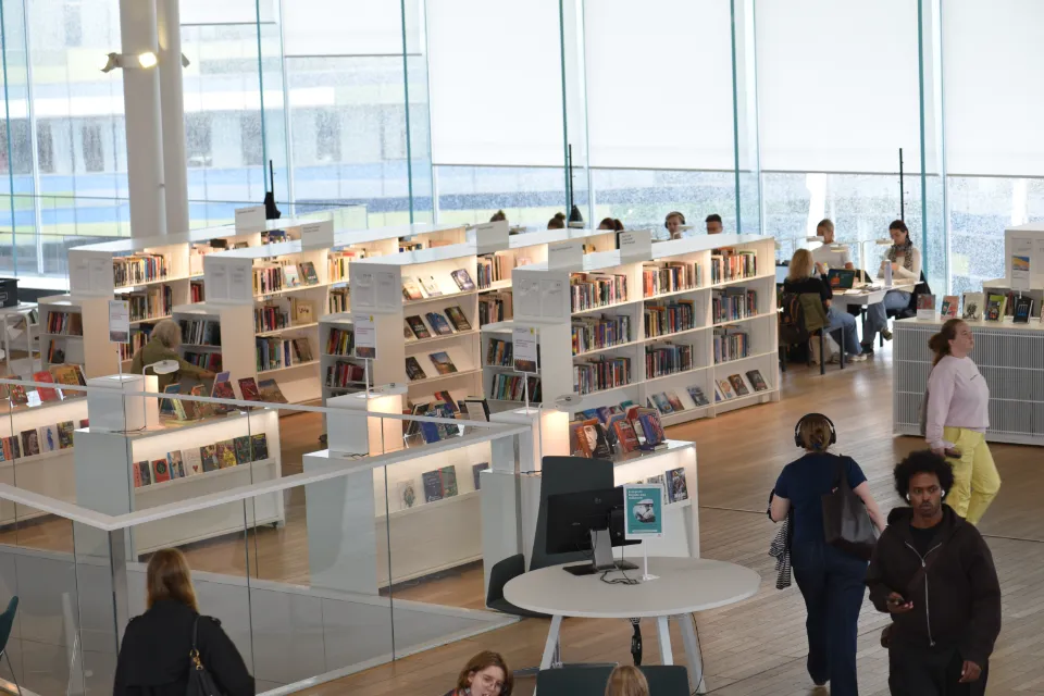Överblick över moderna bokhyllor och besökare i Ode i Helsingfors bibliotek.