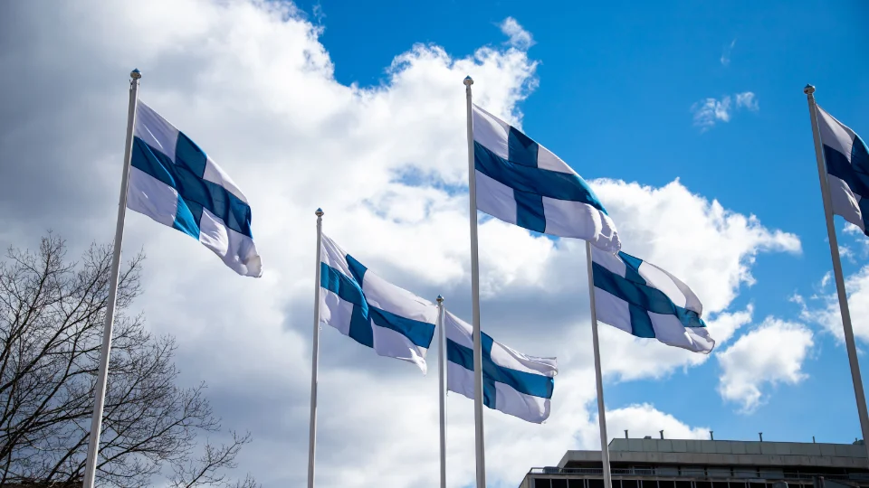 Finland gör en försiktig satsning i rätt riktning Finska flaggor som vajar i vinden mot en blå himmel med moln.
