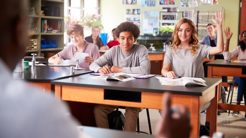 Ny kvalitetsgranskning av gymnasiskolor med inrikning på utveckling Elever i ett klassrum under en naturvetenskapslektion, med några som räcker upp handen för att svara på lärarens fråga.
