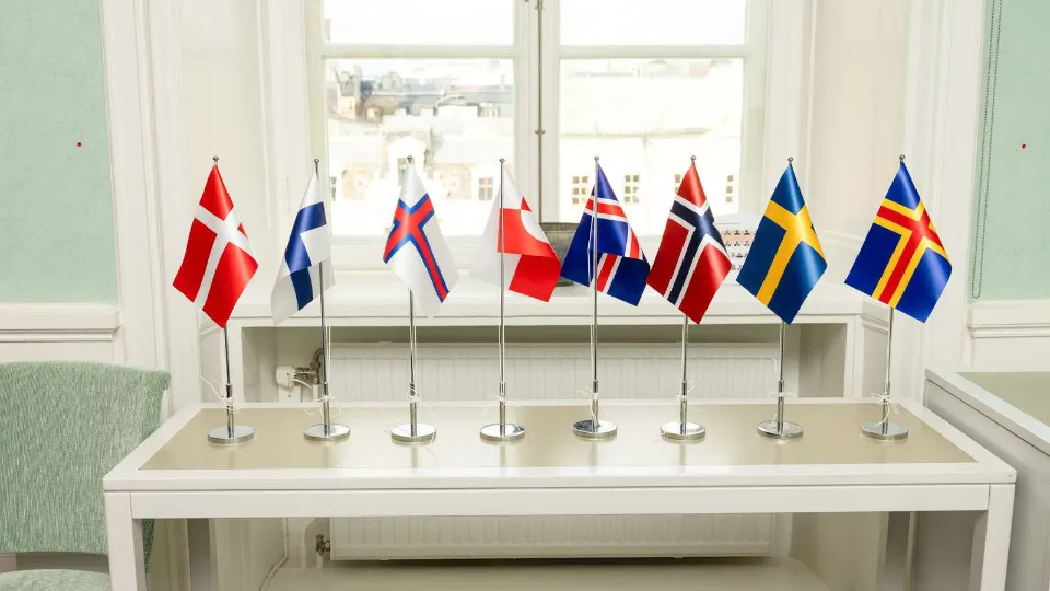 Små nordiske bordflag på en hvidt bord foran et vindue.