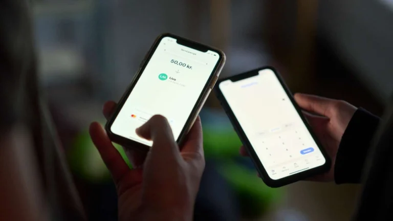 To personer holder smartphones og bruger en digital betalingsløsning til at overføre penge.