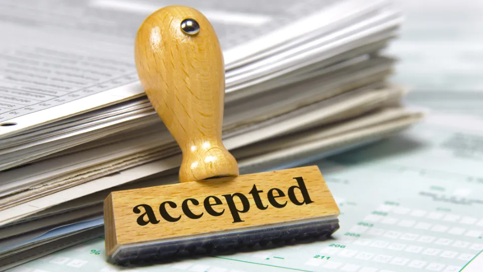 Trestempel med teksten «accepted» foran en bunke dokumenter.