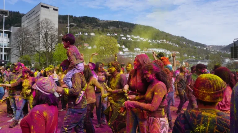 Fargerik Holi-feiring på Festplassen i Bergen, med mennesker dekket av fargepulver.