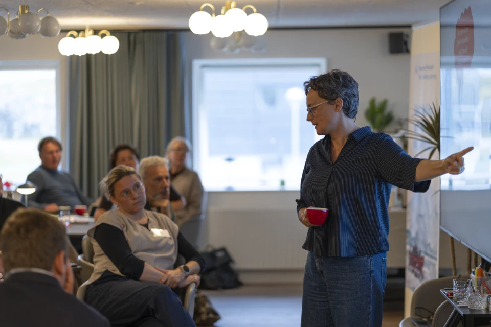 Facilitator ved workshop står foran en tavle og taler til seminarets deltagere i Nuuk.