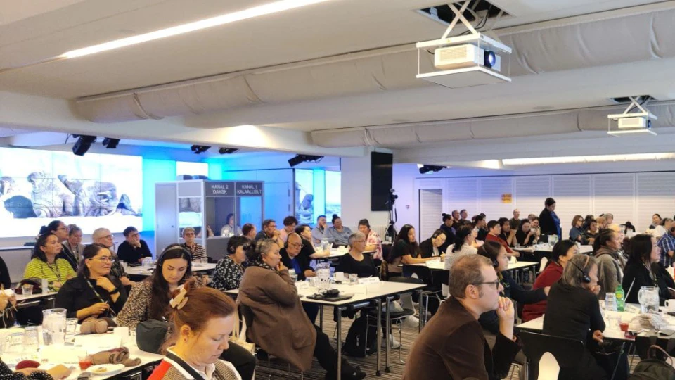 Deltagere ved en vejlederkonference i Nuuk sidder ved borde i et lyst konferencelokale og følger oplægget.